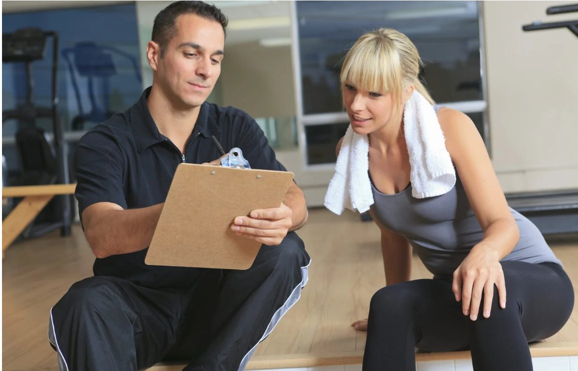 Trainer reviewing a program with a client in the gym